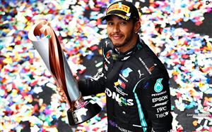 British racing driver Lewis Hamilton posing with his trophy